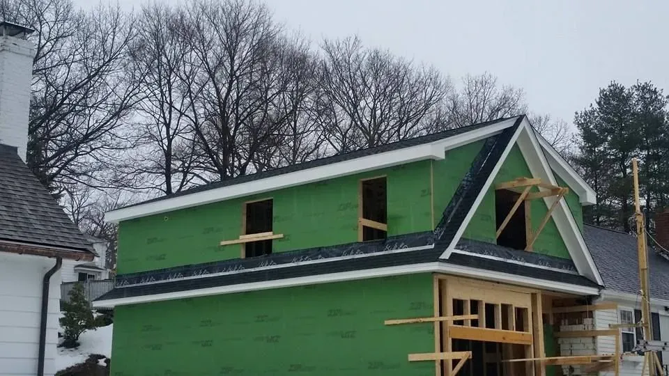 A green house with a black roof is being built.
