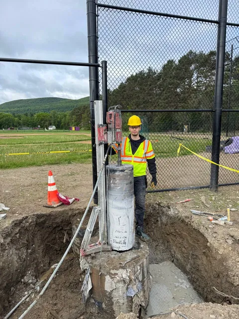 Diamond core drilling rig on large concrete column at outdoor construction site in Massachusetts