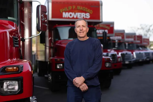 The owner standing in front of a row of red trucks.