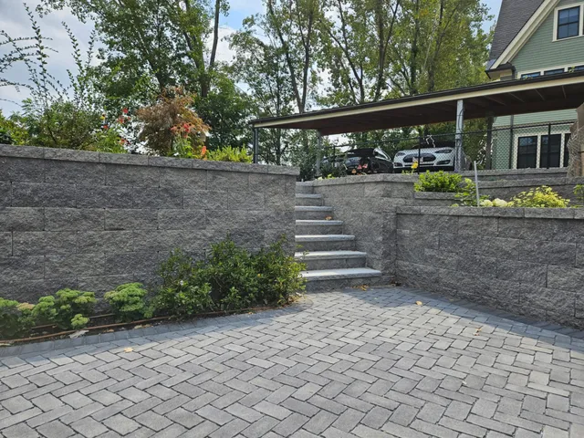 Gray paver patio with modular block retaining wall and integrated steps in Boston, MA
