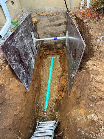 Deep trench with shoring and newly laid sewer pipe