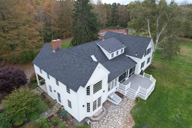 Aerial view of a white house with dark roof and deck