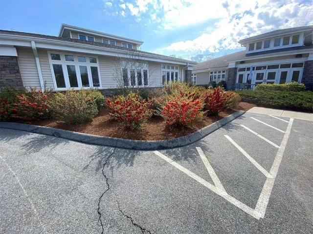 Exterior of a building with landscaping, a parking area, and a blue sky.