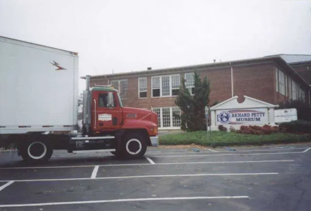 A red truck is parked in front of a building that says richard petite museum