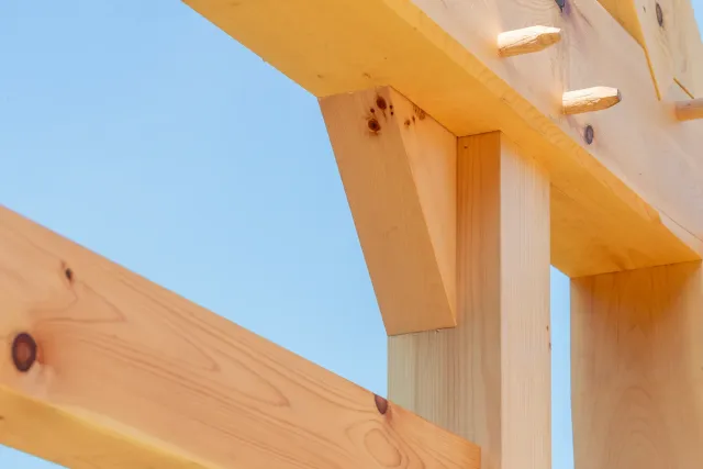 Close-up of a wooden structure, possibly part of a building or furniture, with a blue sky in the background.