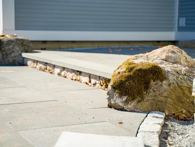 Moss-covered rock beside modern concrete walkway