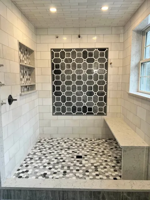 A bathroom with a walk in shower and a bench.