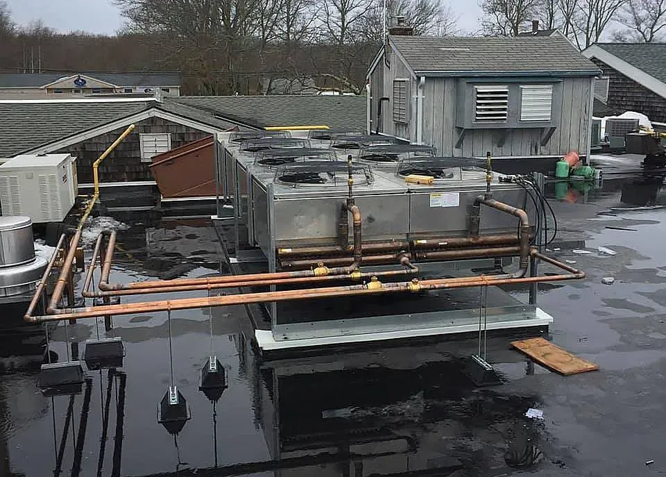 A roof with a lot of pipes on it and a building in the background.