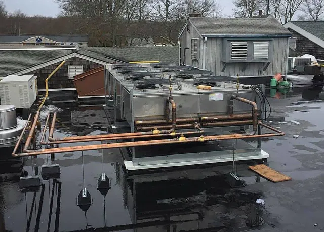 A roof with a lot of pipes on it and a building in the background.