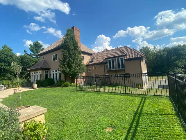 Rear lawn view of a stucco home with a dark seamless gutter system