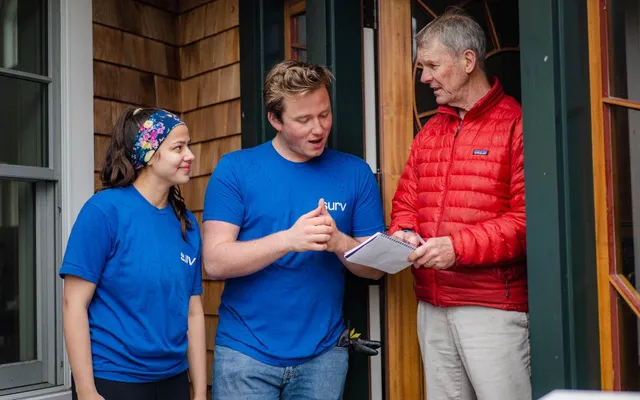Two Surv employees assisting a man in a red jacket
