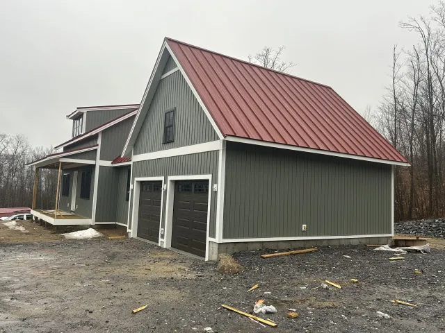 A garage with a red roof is being built next to a house.