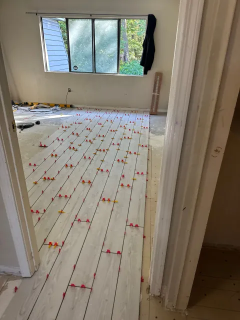 Empty room with white floorboards, open windows, and red confetti scattered across the floor