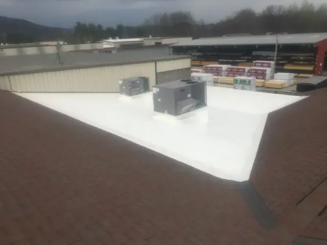 Commercial building with brown shingle roof and white flat roof, featuring HVAC units.
